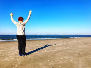 Full length rear view of woman walking on beach