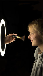 Side view of woman holding cigarette against black background