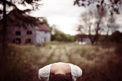 Woman bending over against house