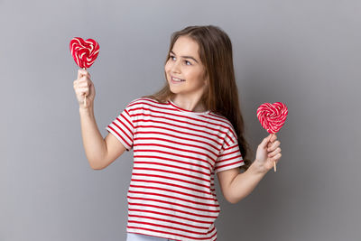 Midsection of woman holding heart shape against wall