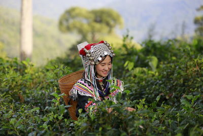 Woman with basket by tea crops on field