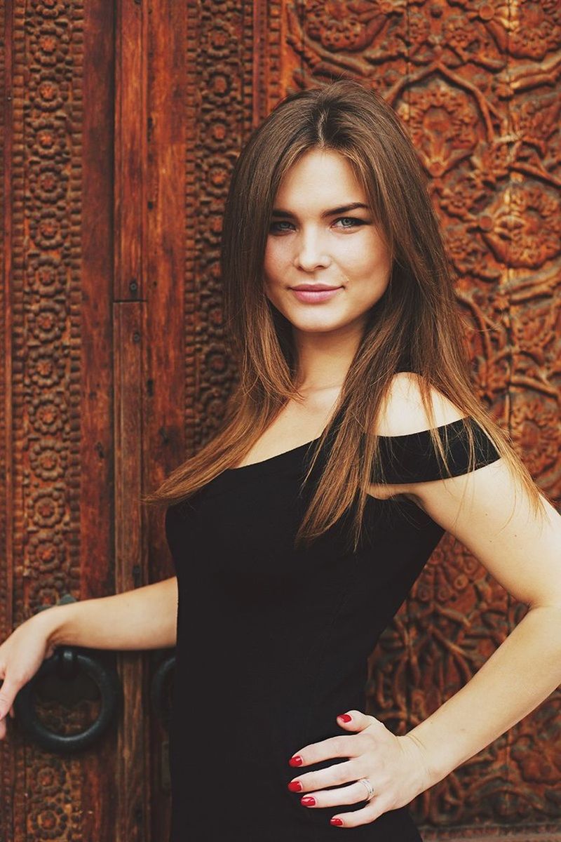 PORTRAIT OF YOUNG WOMAN STANDING IN DOOR