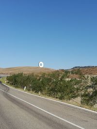 Scenic view of road against clear blue sky and original monument