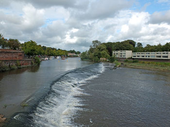 Scenic view of river by buildings against sky