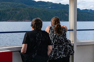 Rear view of woman looking at sea against mountain