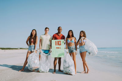 Portrait of activist holding plastic bags while standing at beach