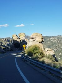 Road by rock formations against blue sky