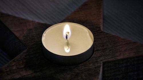High angle view of illuminated candle on wooden star shape