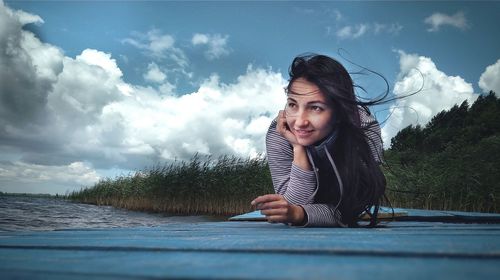 Happy young woman against trees against sky