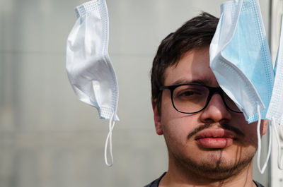 Close-up portrait of young man holding eyeglasses