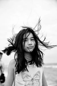 Girl holding hair and standing at shore