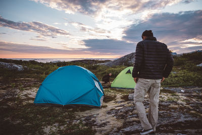 2 men in campsite at sunset on cloudy sky