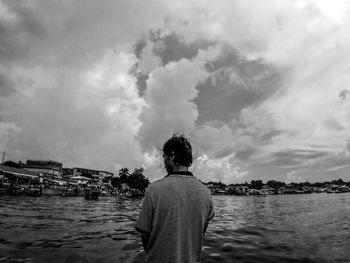 Rear view of man standing by sea against sky