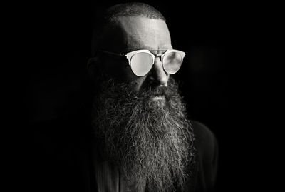 Bearded man wearing sunglasses against black background