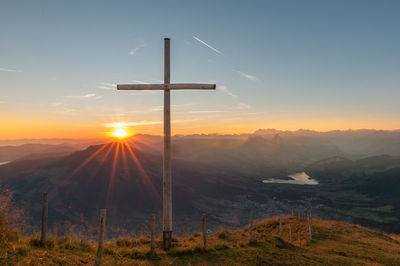 Cross on mountain against sky during sunset