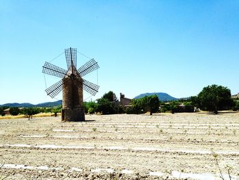 Traditional windmill on landscape against clear sky