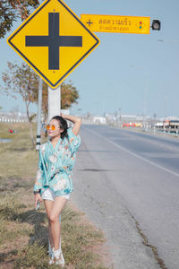 Full length of woman standing on road by sign