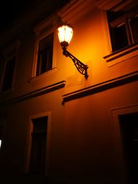 Low angle view of illuminated light bulb hanging at night