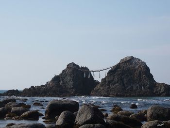 Rocks on beach against clear sky