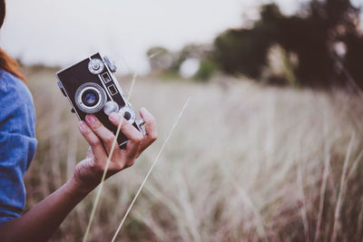 Midsection of woman holding camera on field