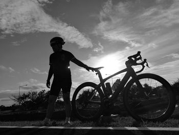 Full length of silhouette man riding bicycle against sky