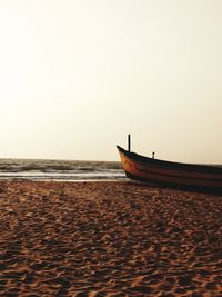 Boat moored on beach against clear sky