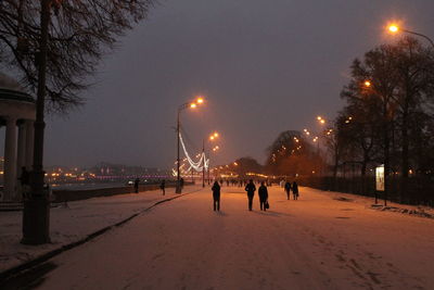 People on illuminated street during winter at night