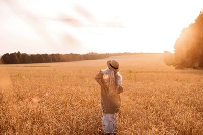 Rear view of woman standing on field against sky