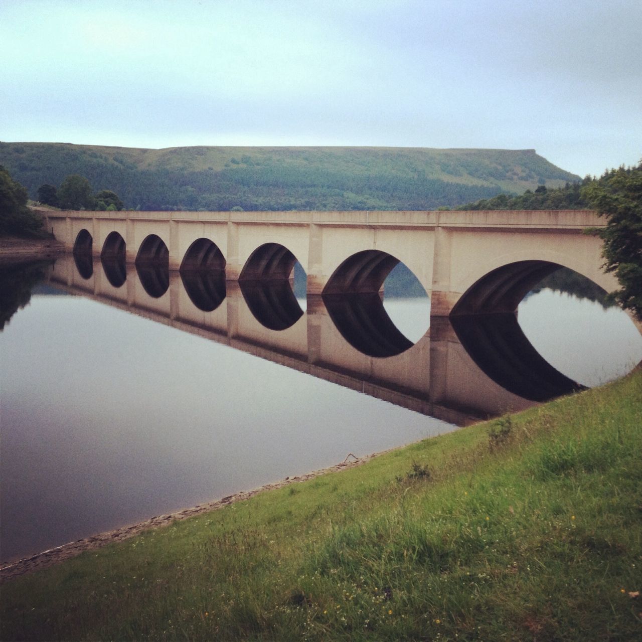 grass, clear sky, sky, built structure, tranquility, architecture, landscape, bridge - man made structure, tranquil scene, mountain, field, nature, water, connection, copy space, river, day, outdoors, no people, transportation