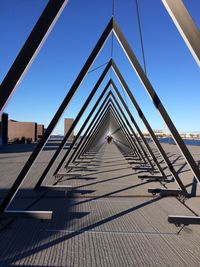 Triangle shaped walkway at promenade against clear blue sky