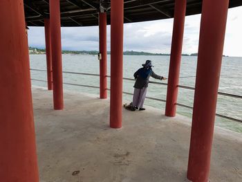 Rear view of men standing by sea against sky