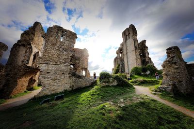 People at old ruin building against sky