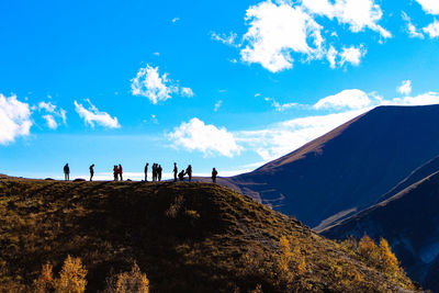 People on landscape against blue sky