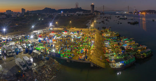 High angle view of illuminated city by sea at night