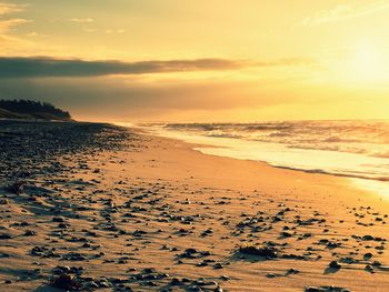 Stones and water trails in beach sand. traces on beach at smooth sea, coastline in summer evening