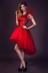 Beautiful young woman in fashion red dress posing in studio