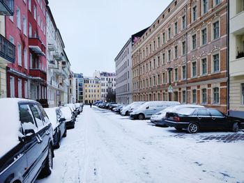 Vehicles on road amidst buildings in city during winter