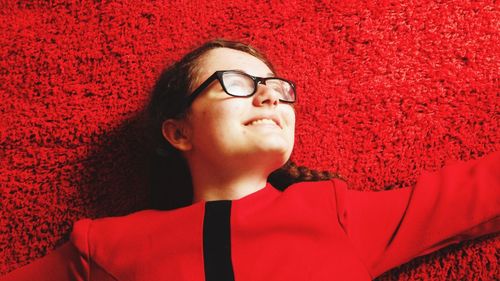 High angle view of smiling young woman lying on red rug