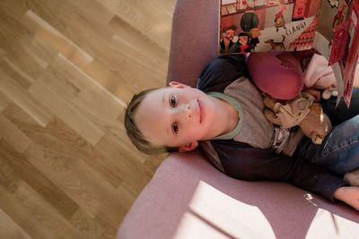 Areal view of a boy sitting on a chair reading at home