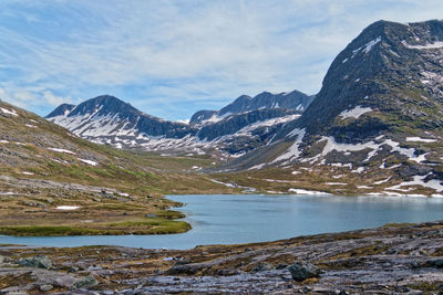 Scenic view of lake by snowcapped mountains against sky