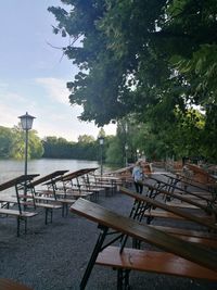 Chairs and table by river against sky