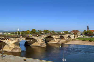 Arch bridge over river against clear blue sky