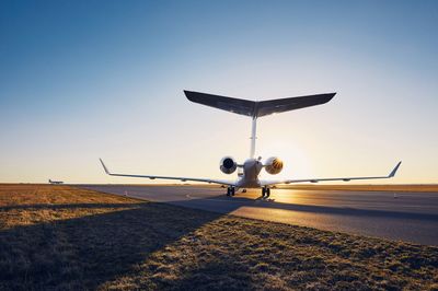 Airplane on runway against clear blue sky during sunset