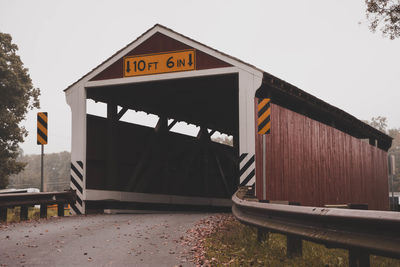 Information sign by built structure against sky