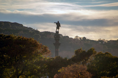 Statue of trees against cloudy sky