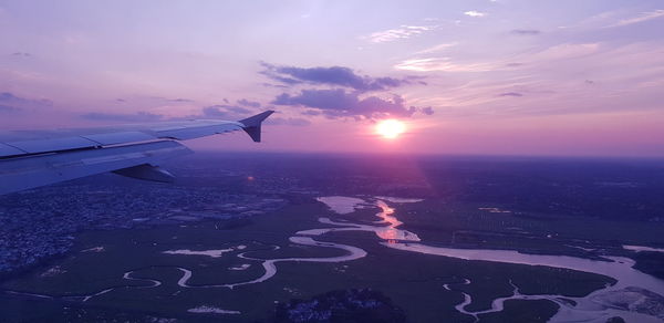 Airplane flying over sea against sky during sunset