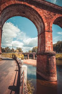 Arch bridge over river against sky