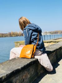 Rear view of woman against blue sky on sunny day