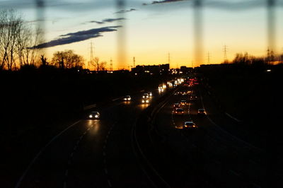 Cars on road against sky during sunset