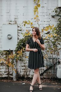 Portrait of beautiful woman smiling while standing against wall